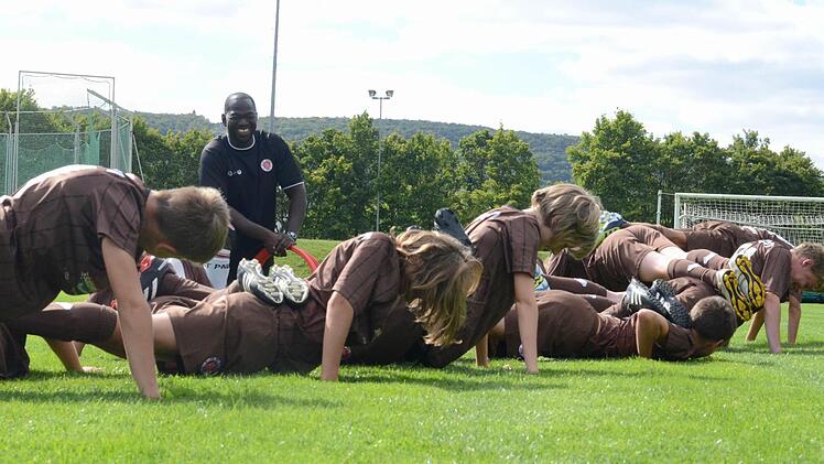 Bilal Afrane, Trainer in der Fußbalschule des FC St. Pauli, lässt die Kinder im Sportpark eine Liegestütz-Übung machen, die nur funktioniert, wenn alle mitmachen. Foto: Jürgen Schmitt
