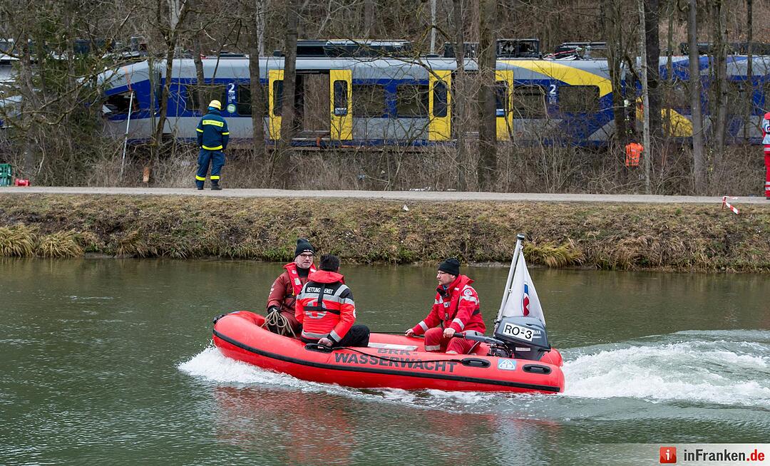 . Helfer des Roten Kreuzes fahren am 10.02.2016 mit einem Boot an der Unfallstelle eines Zugunglücks in der Nähe von Bad Aibling (Bayern) vorbei. Die Polizei und andere Experten wollen herausfinden, wie es zu dem Zug-Unglück in Bayern kam. Foto: Sven Hoppe/dpa