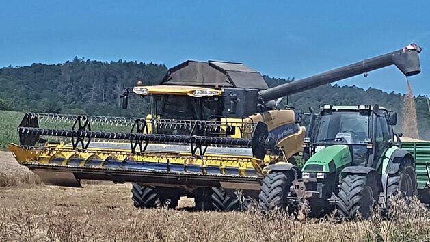 Ein M&auml;hdrescher des Unternehmens Paulus ist auf einem Feld bei Unterpreppach unterwegs.   Die riesige landwirtschaftliche Maschine  f&uuml;llt das Getreide aus dem  K&ouml;rnertank auf einen Anh&auml;nger. Fotos: Helmut Will