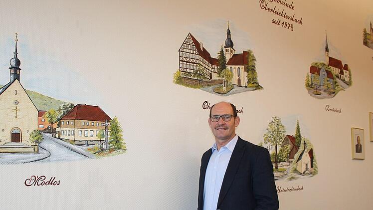 Dieter Muth steht im Konferenzzimmer des Rathauses der Gemeinde Oberleichtersbach. Die fünf Gemeindeteile sind an der Wand verewigt.  Foto: Julia Raab