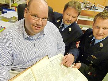 Stadtbücherei-Leiter Michael Scholz (links) hat gemeinsam mit den Feuerwehr-Führungskräften Bernd Eichhorn und Markus Wolf (rechts) für das heutige Feuerwehr-Jubiläum in Fischbach tief in historischen Unterlagen gekramt. Foto: Lothar Weidner