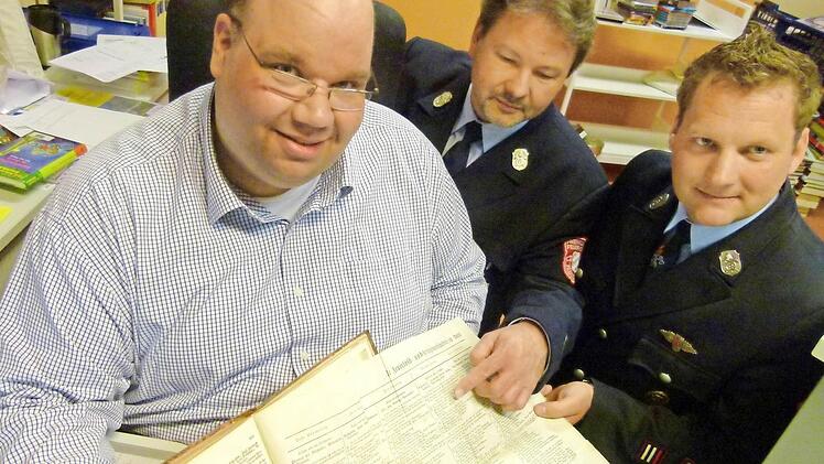 Stadtbücherei-Leiter Michael Scholz (links) hat gemeinsam mit den Feuerwehr-Führungskräften Bernd Eichhorn und Markus Wolf (rechts) für das heutige Feuerwehr-Jubiläum in Fischbach tief in historischen Unterlagen gekramt. Foto: Lothar Weidner