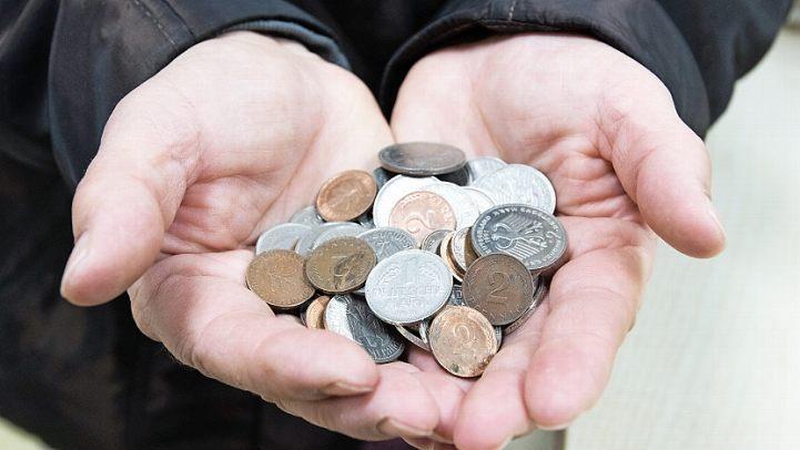 Eine Frau mit einer Handvoll D-Mark-Stücken und Pfennigen. Die Bundesbürger haben Millionen Mark in Einkaufstüten und Zigarrenkisten gebunkert. Foto: Julian Stratenschulte, dpa