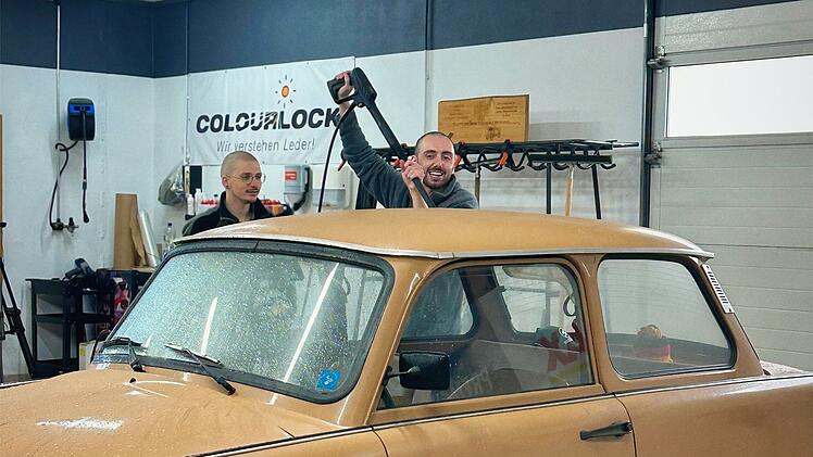 Timur Turga (rechts) soll mit einem Hochdruckreiniger einen Oldtimer wieder zum Gl&auml;nzen bringen.