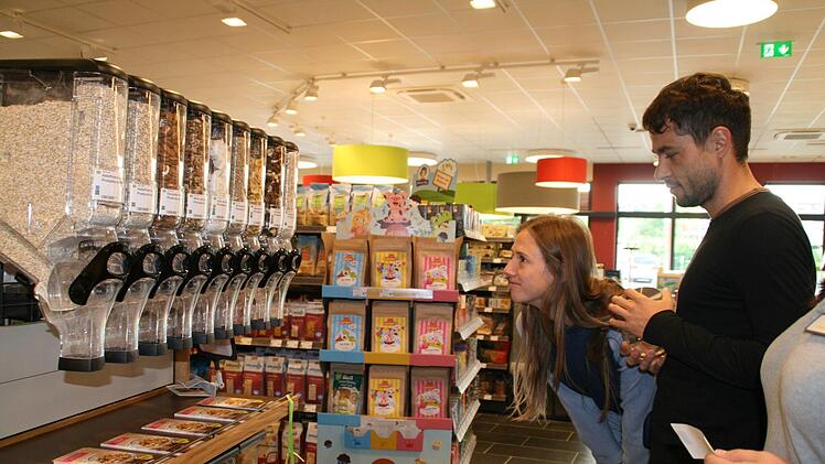 Bezirksleiter Karsten Lindlein hat den Kunden erklärt, wie es geht, Mira Weirathe und Martin Trischler probieren es aus: Unverpackt einkaufen bei "denn's" Biomarkt.  Foto: Anja Vorndran
