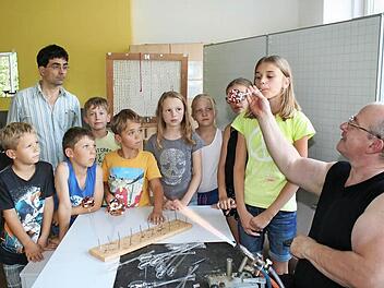 Die elfjährige Tina pustet voll konzentriert, damit die Kugel nur ja nicht zerspringt. Auch Claudio Pütz, der Rektor der Pommersfeldener Schule (Zweiter von links), ist von der Glasbläserei sichtlich gefesselt.  Foto: Evi Seeger