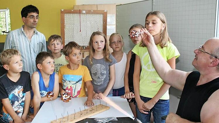 Die elfjährige Tina pustet voll konzentriert, damit die Kugel nur ja nicht zerspringt. Auch Claudio Pütz, der Rektor der Pommersfeldener Schule (Zweiter von links), ist von der Glasbläserei sichtlich gefesselt.  Foto: Evi Seeger