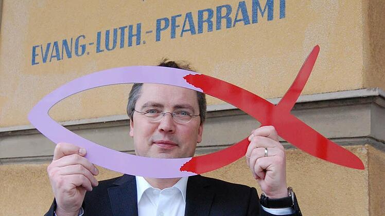 Pfarrer Wilde mit dem Zeichen der Kirchenvorstandswahl.
