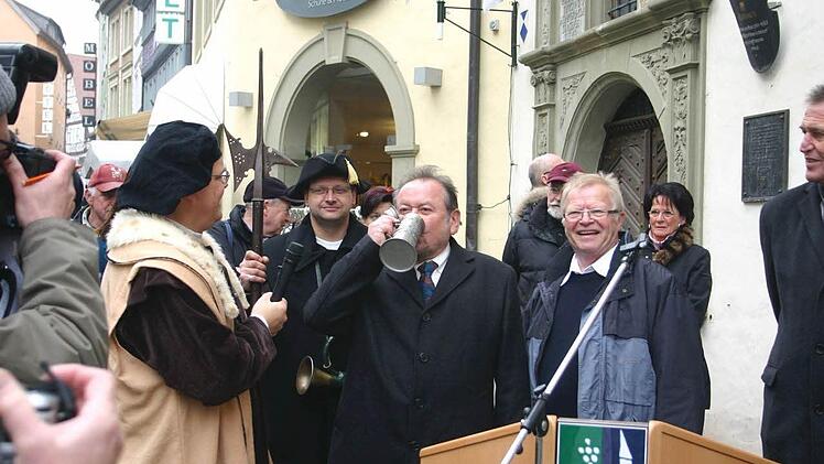 Bürgermeister Erich Hegwein besiegelt mit dem traditionellen Schluck auch der Kandel vor dem Kitzinger Rathaus die Eröffnung der Schifffahrt von Marktbreit nach Kitzingen mit Oberbürgermeister Siegfried Müller (ganz rechts). Foto: Thomas Meyer