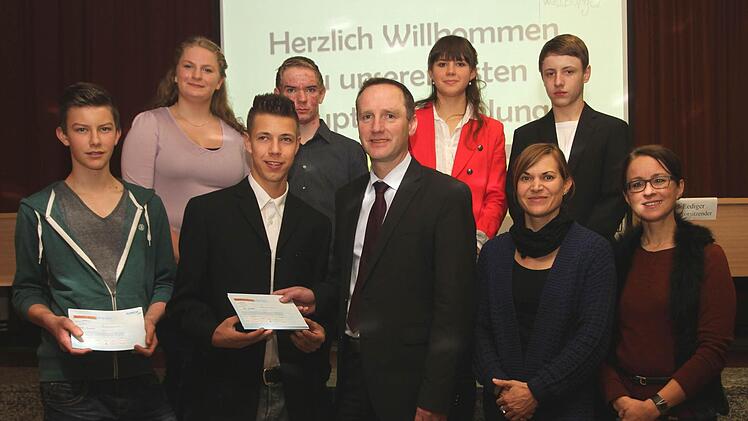 Feierlich wird die erste Aktie verkauft, und zwar an Bürgermeister Michael Ziegler. Mit im Bild Moritz Kundmüller, Patrik Lediger, Ziegler, Susanne Müller und Beate Reiser (vordere Reihe von links) sowie Sarah-Marie Jansen, Sebastian Postler, Anna Schneider und Lars Oppermann (hintere Reihe von links). Foto: Günther Geiling