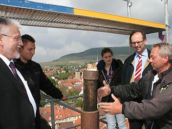 Peter Büttner (rechts) erklärt Bürgermeister Josef Mend (links) und Pfarrer Hans Reeg, wie das Kreuz künftig hoch oben auf der Kirchturmspitze befestigt wird. Foto: Daniela Röllinger