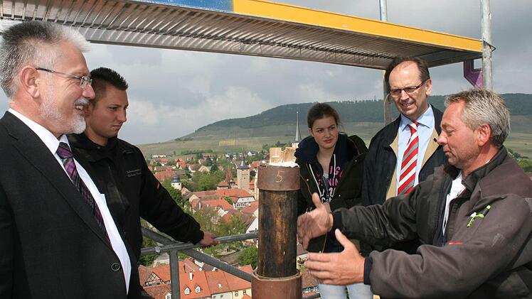 Peter Büttner (rechts) erklärt Bürgermeister Josef Mend (links) und Pfarrer Hans Reeg, wie das Kreuz künftig hoch oben auf der Kirchturmspitze befestigt wird. Foto: Daniela Röllinger