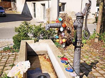 Statt des üblichen Osterbrunnenschmucks wird der "Hutzelbrunnen" in Fatschenbrunn in diesem Jahr von bunten Steinen geziert, die die Kinder des Dorfes gestalteten und dann am Brunnen ablegten.  Fotos: sw