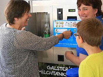 Helga Deinhardt holt sich ihre erste Flasche Milch aus dem Automaten, rechts Christine Galster und Elias, der den Tankvorgang interessiert beobachtet.  Fotos: Franz Galster
