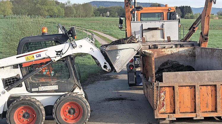Mit einem kleinen Schaufelbagger wird der Müll in einen Container geworfen und dann entsorgt.