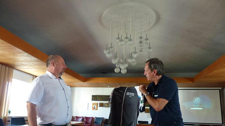 Organisator Wolfgang Slama (r.) vom Bayerischen Rundfunk zeigt Andreas Galster  das Tour-Hemd. Foto: Pauline Lindner