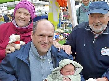 Willkommen daheim: Schon wenige Stunden nach der Geburt ihrer kleinen Tochter Lucie sind Michaele und Rainer Strobl (Mitte) wieder an ihren Stand auf dem Pfingsthandwerkermarkt zurückgekehrt. Dort wurden sie von Wolfgang Dultz, dem Vorsitzenden des Museums-Fördervereins, mit einen kleinen Schäfchen zur Erinnerung an diesen großen Tag empfangen. Foto: Gabi Bertram