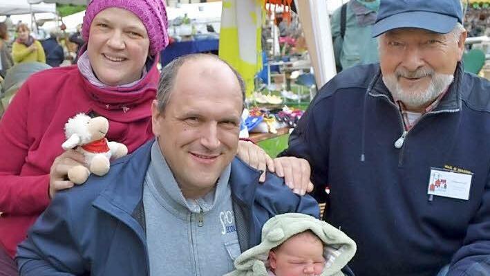 Willkommen daheim: Schon wenige Stunden nach der Geburt ihrer kleinen Tochter Lucie sind Michaele und Rainer Strobl (Mitte) wieder an ihren Stand auf dem Pfingsthandwerkermarkt zurückgekehrt. Dort wurden sie von Wolfgang Dultz, dem Vorsitzenden des Museums-Fördervereins, mit einen kleinen Schäfchen zur Erinnerung an diesen großen Tag empfangen. Foto: Gabi Bertram