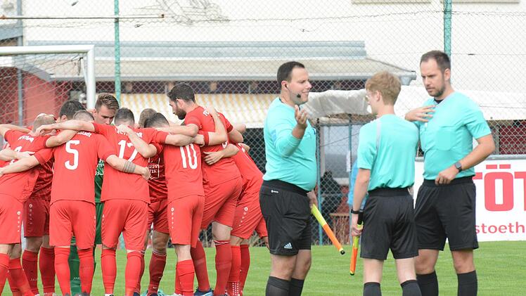 Als Team verstehen sich auch die Schiedsrichter, die sich ebenso auf ein Spiel einstimmen wie in diesem Fall der FC Fuchsstadt im Hintergrund. Foto: ssp