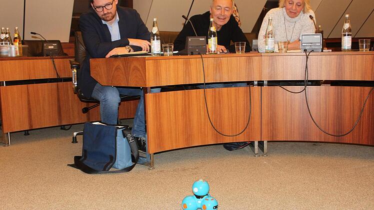 Dash, der Spielzeug-Roboter, sorgt bei den Stadträten für neugierige Blicke; von links Ralf Schneider, Günter Reinlein und Monika Faber aus der SPD-Fraktion bei einer Sitzung des Ausschusses für Stadtentwicklung, in der neue Medien der Stadtbücherei vorgestellt wurden. Popp