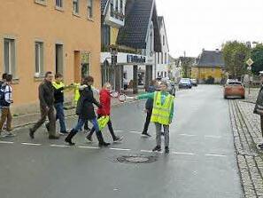 Polizeihauptmeister Ralf Maisel (von rechts) und Polizeihauptkommissar Hermann Dörfler zeigen den neuen Schülerlotsen die richtige Handhabung der Winkerkelle am Übergang an der Marktstraße. Mit im Bild inmitten der Schüler Konrektor Theo Schramm. Foto: Klaus-Peter Wulf