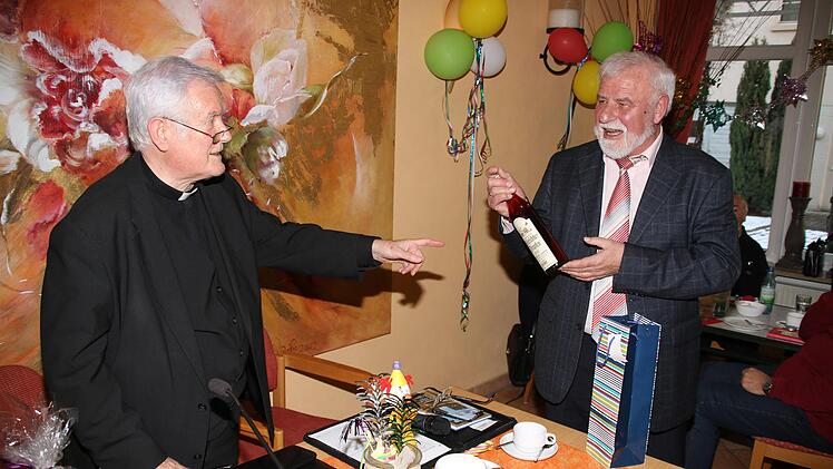 Eine Flasche "Mürschter Tropfen" überreichte Erzählcafé-Organisator Eugen Albert (rechts) dem emeritierten Würzburger Bischof Friedhelm Hofmann. Natürlich bekam er auch die obligatorische Tasse. Foto: Dieter Britz