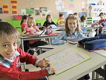 Die Tischplatte ist abgesenkt. Robert, der sich beim Schreiben anstrengen muss, weil seine Hände spastisch sind, fühlt sich in seiner Klasse sichtlich wohl. Seit zwei Jahren rollt er bereits durch die Volksschule Weitramsdorf.  Fotos: Beate Deuerling