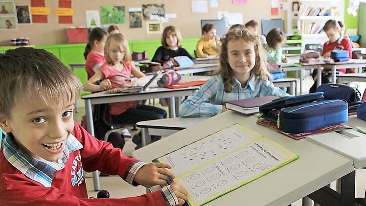 Die Tischplatte ist abgesenkt. Robert, der sich beim Schreiben anstrengen muss, weil seine Hände spastisch sind, fühlt sich in seiner Klasse sichtlich wohl. Seit zwei Jahren rollt er bereits durch die Volksschule Weitramsdorf.  Fotos: Beate Deuerling