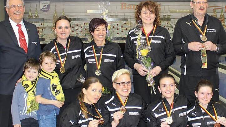 Der alte und neue deutsche Meister pr&auml;sentiert sich bei der Siegerehrung, hinten v.&nbsp;l.: DKBC-Pr&auml;sident J&uuml;rgen Franke, Daniela Kicker, Beate Fritzmann, Beata Wlodarczyk, Betreuer Harald Gr&auml;tzsch; vorn v.&nbsp;l.: zwei junge Fans, Ioana Antal, Sina Bei&szlig;er, Sabrina Imbs, Vanessa Welker. Auf dem Bild fehlen Corinna Kastner und Betreuerin Sabrina Walter. Foto: privat