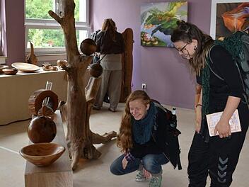 Waleria Sadkow und Johanna Owsian von der Holzbildhauerschule in Empfertshausen interessieren sich für die Objekte des Holzkünstler Jess Cobb. Foto: Andreas Lomb