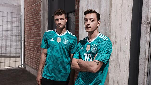 Die deutschen Fußballnationalspieler Thomas Müller (l) und Mesut Özil im grünen Auswärtstrikot für die Fußball-Weltmeisterschaft in Russland 2018. Die Spieler werden damit am 23.03.2018 das erste Mal im Länderspiel Deutschland gegen Spanien auflaufen. Foto: adidas /dpa