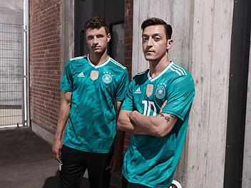 Die deutschen Fußballnationalspieler Thomas Müller (l) und Mesut Özil im grünen Auswärtstrikot für die Fußball-Weltmeisterschaft in Russland 2018. Die Spieler werden damit am 23.03.2018 das erste Mal im Länderspiel Deutschland gegen Spanien auflaufen. Foto: adidas /dpa