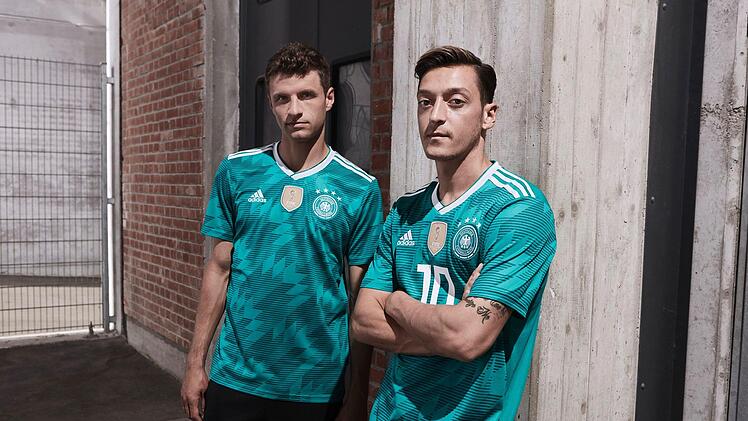 Die deutschen Fußballnationalspieler Thomas Müller (l) und Mesut Özil im grünen Auswärtstrikot für die Fußball-Weltmeisterschaft in Russland 2018. Die Spieler werden damit am 23.03.2018 das erste Mal im Länderspiel Deutschland gegen Spanien auflaufen. Foto: adidas /dpa