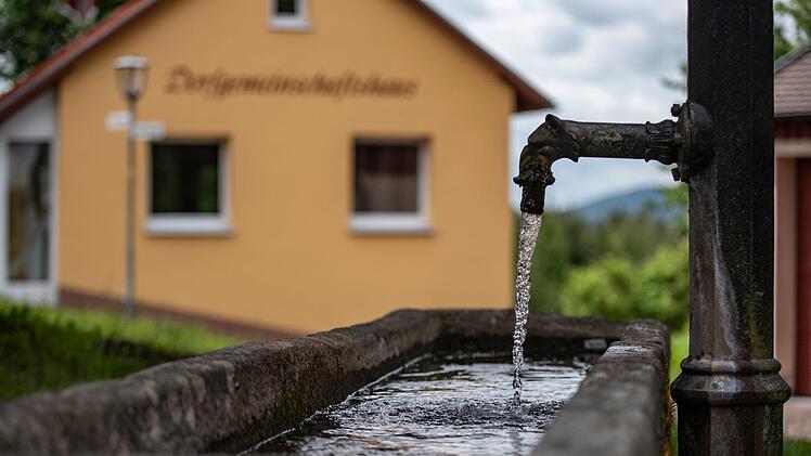 Ein Brunnen mit Steintrog und Sitzgruppe bietet Rastmöglichkeit in  Kilianshof, bevor der Aufstieg beginnt. Foto: Jürgen Hüfner