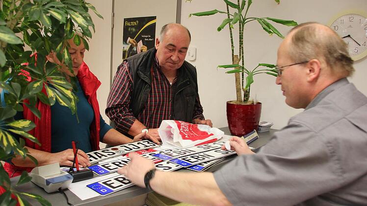 Rudi Schmidt beklebt die neuen Schilder der Schlögls mit dem amtlichen Siegel des Landratsamtes (Haßberge).