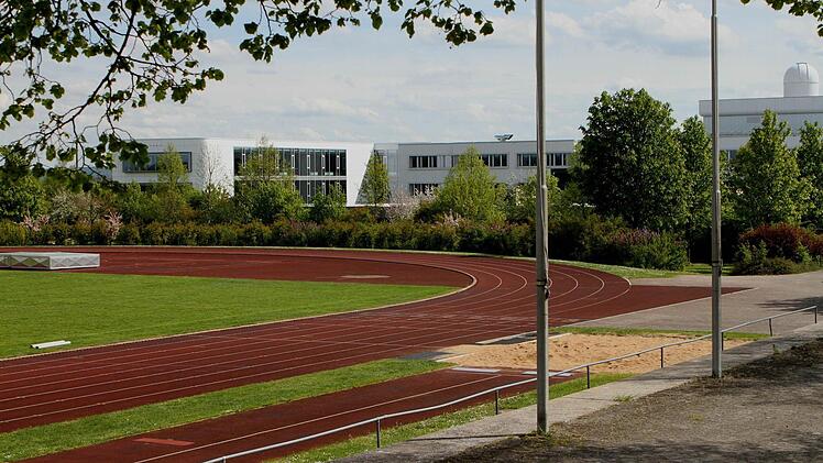 Blick über die Sprunggrube und die 400-Meter-Laufbahn, die in den bevorstehenden Sommerferien saniert werden sollen. Der Rasen wird vorerst nicht erneuert. Im Hintergrund sind die Gebäude des Schulzentrums Haßfurt zu sehen. Foto: Günther Geiling