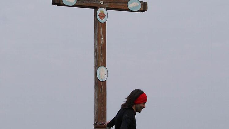 Ein einsamer L&auml;ufer joggt an einem Kruzifix am Wegesrand vorbei. Foto: Mario Deller