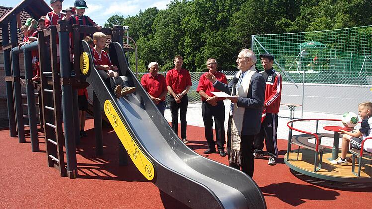 Einer neuen Verwendung führte der FC Eltingshausen einen ehemaligen Tennisplatz zu: Minifußballfeld und Spielgelände. Auf unserem Foto segnet Pfarrer Edwin Ziegler die Anlage, während die Kinder bereits die Rutsche belagern. Im Hintergrund von links Roland Metzler, Michael Seufert und Gerhard Fischer.  Foto: Stefan Gegiger