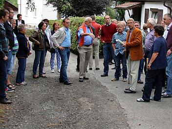 Ist die Straße "Am Greinberg" noch verkehrssicher oder muss sie dringend saniert werden? Diese Frage versuchten die Weitramsdorfer Gemeinderäte, angeführt von Bürgermeister Wolfgang Bauersachs (im braunen Sakko), am Dienstagabend vor Ort zu klären. Eine knappe Mehrheit sah später bei der Abstimmung akuten Handlungsbedarf. Foto: Bettina Knauth