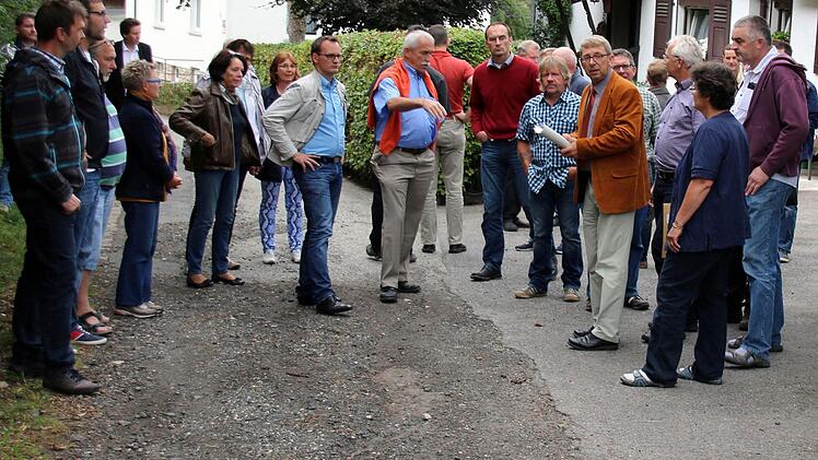 Ist die Straße "Am Greinberg" noch verkehrssicher oder muss sie dringend saniert werden? Diese Frage versuchten die Weitramsdorfer Gemeinderäte, angeführt von Bürgermeister Wolfgang Bauersachs (im braunen Sakko), am Dienstagabend vor Ort zu klären. Eine knappe Mehrheit sah später bei der Abstimmung akuten Handlungsbedarf. Foto: Bettina Knauth