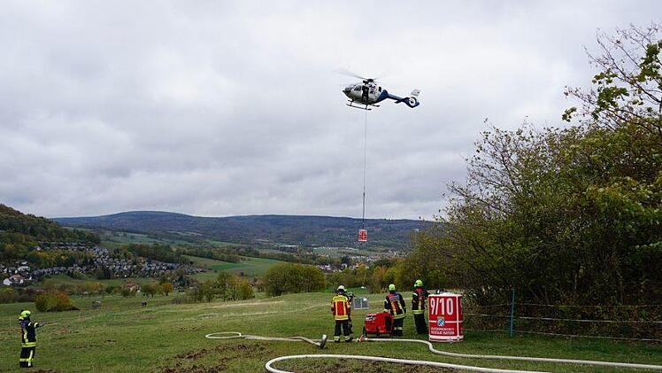Mit geübten Griffen hängten die Flughelfer den Außenlastbehälter an den  Helikopter. Foto: Marion Eckert