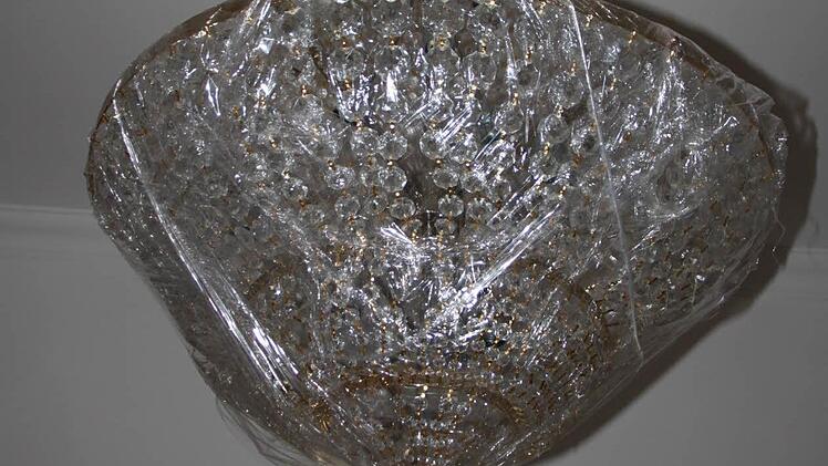 An der Decke - noch verpackt - hängt ein riesiger Kronleuchter.