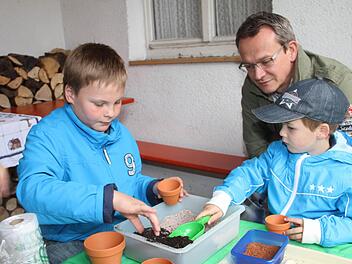 Clemens Weiß (links) und Lukas Hauck (rechts) entdecken ihre gärtnerischen Fähigkeiten beim Säen von Kressesamen in Blumentöpfen. Vater Alexander Hauck schaut zu. Fotos: Gerda Völk