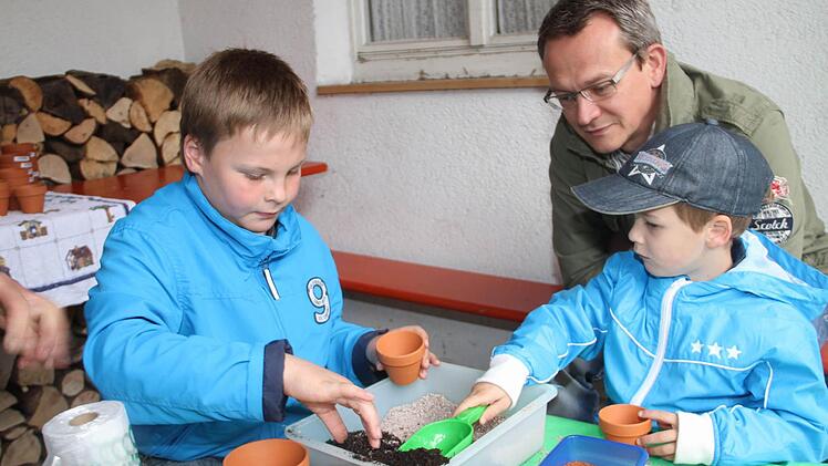 Clemens Weiß (links) und Lukas Hauck (rechts) entdecken ihre gärtnerischen Fähigkeiten beim Säen von Kressesamen in Blumentöpfen. Vater Alexander Hauck schaut zu. Fotos: Gerda Völk