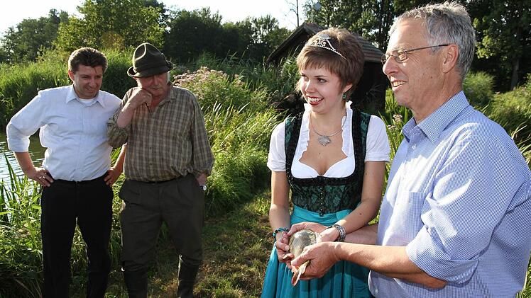 Thomas Speierl (l.) und Fritz Nagel schauen zu, wie Karpfenkönigin Katrin I. und Robert Klupp einen fangfrischen Karpfen in Händen halten.  Foto: Erlwein