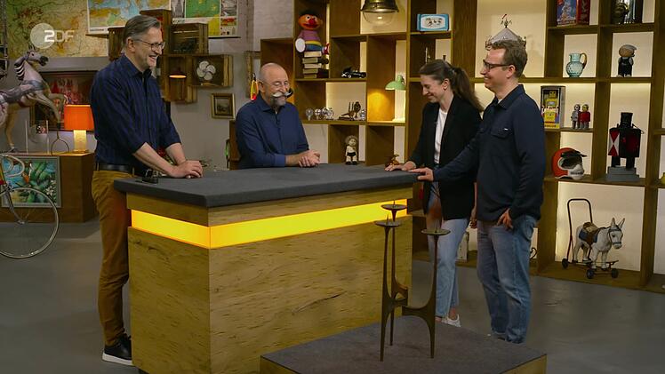 Ein Kerzenständer sorgte bei "Bares für Rares" für gemischte Reaktionen, von links: Experte Detlev Kümmel, Moderator Horst Lichter, Kandidaten Marisa und Christopher.