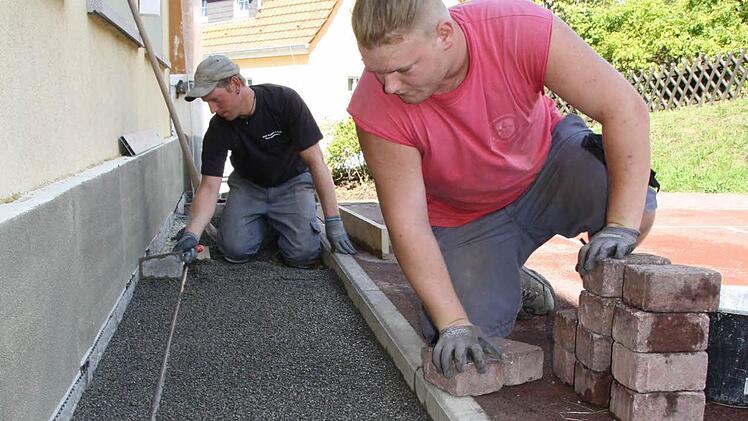 Ralf Zimmermann (links) und Fabian Bötsch pflastern den Bereich um den sanierten Teil der Bad Brückenauer Grundschule. Fotos: Ralf Ruppert