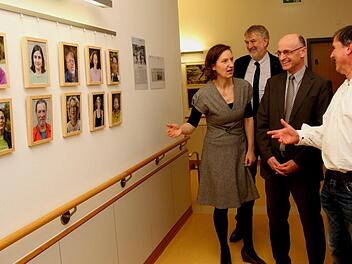 Tina Lenhart von der Gesundheitsregion plus, Klinik-Vorstand Stephan Kolck, Landrat Wilhelm Schneider und Herbert Ritter (von links) mit Teilnehmern vor Bildern .