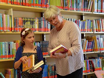 Amelie Götz hat die meisten Bücher im Regal hinter ihr schon gelesen. Deshalb sucht sie mit der Leiterin der Katholischen Öffentlichen Bücherei, Elisabeth Kuhn, nach einem neuem Lesestoff.  Foto: Kathrin Kupka-Hahn
