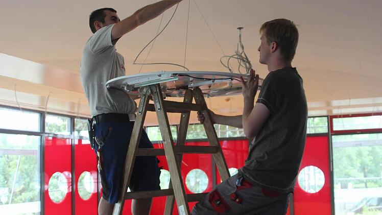 Die Elektriker Wolfgang Wendler (links) und Maik Rosenbauer hängen Lampen auf.